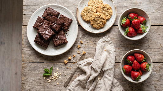 Mesa de repostería casera con brownie de chocolate negro, galletas de avena y fresas frescas